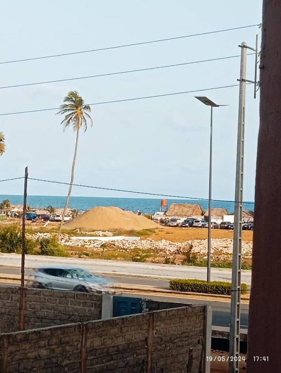 a car driving down a street with a palm tree and the ocean at Richie club des rois in Agonkamè