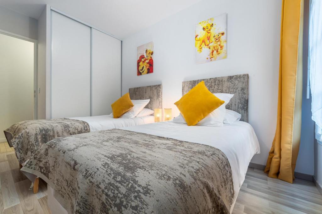 - 2 lits dans une chambre d'hôtel avec des oreillers jaunes dans l'établissement Disneyland Paris 6 Pers- WIFI - Disney TV Wifi, Parking, à Chessy