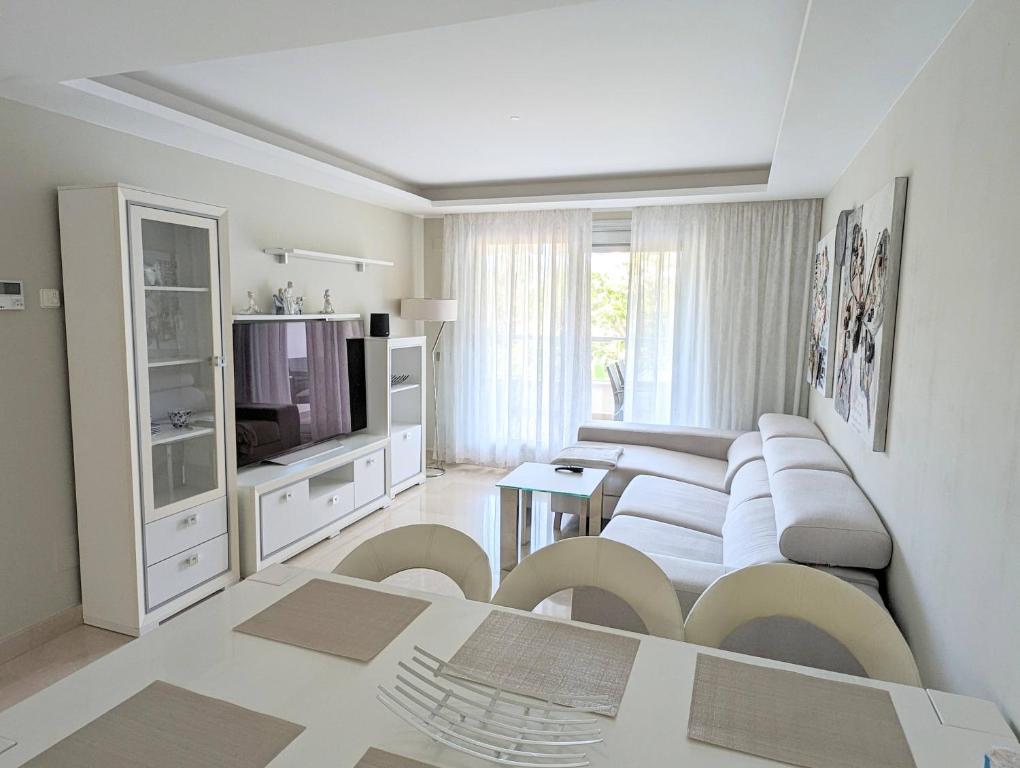 uma sala de estar com mobiliário branco e uma televisão em Apartments 1418 San Pedro em Marbella