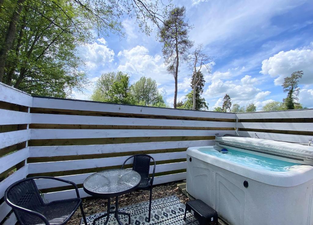 a hot tub and a table and chair next to a fence at Magpie 6 HuntersMoon-Warminster-longleat-Bath in Warminster