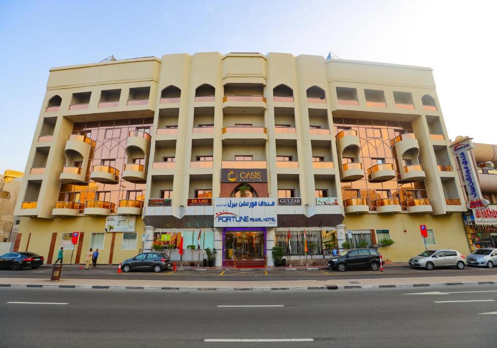 un gran edificio con coches estacionados frente a él en Fortune Pearl Hotel, en Dubái