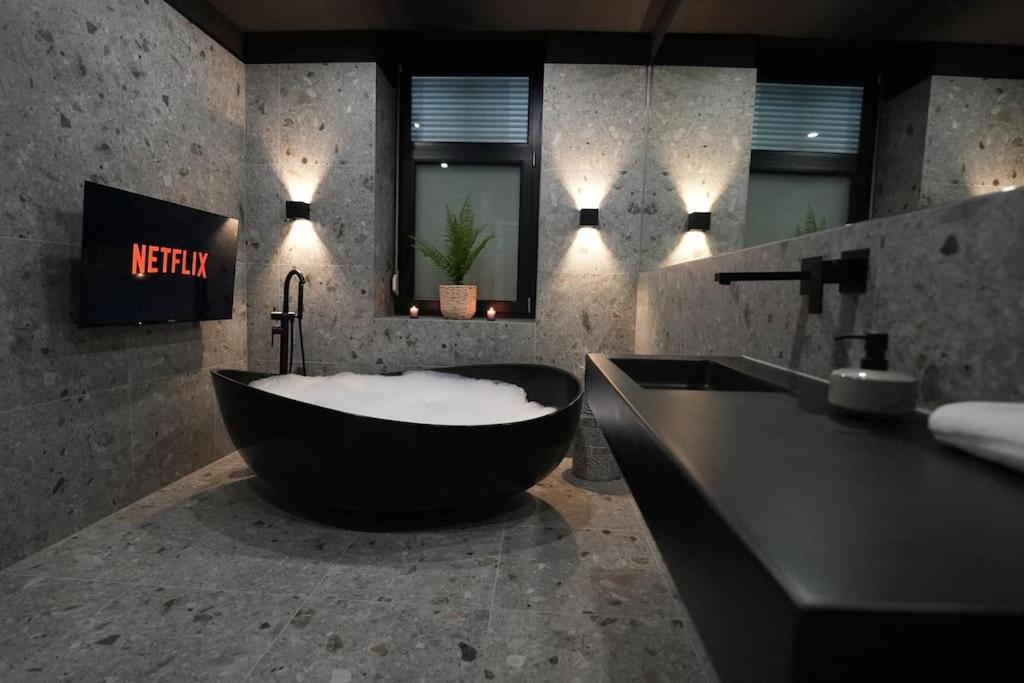 a bathroom with a black tub and a sink at Luxusapartment mit Badewanne und Parkplatz in Graz