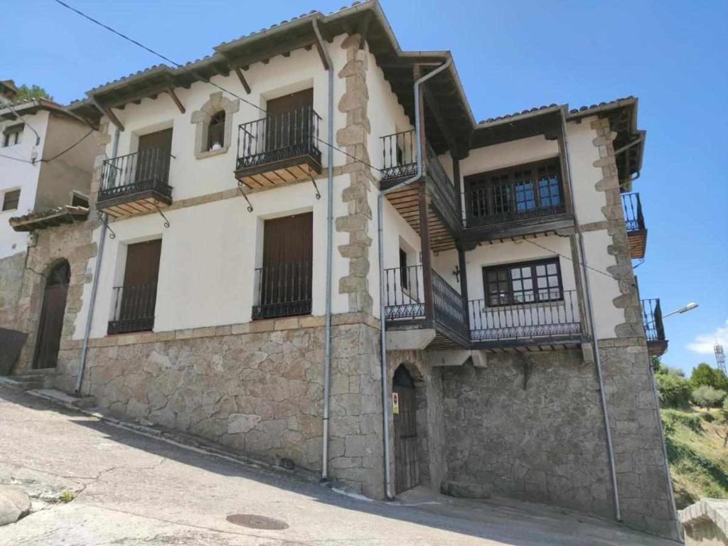 an old stone house with balconies on a street at Casa Rural El Mirador del Pico in Santa Cruz del Valle