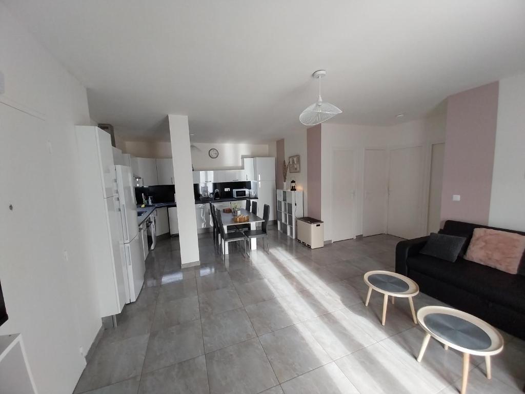 un salon avec un canapé noir et une cuisine dans l'établissement Appartement Gournay-sur-Marne, à Gournay-sur-Marne