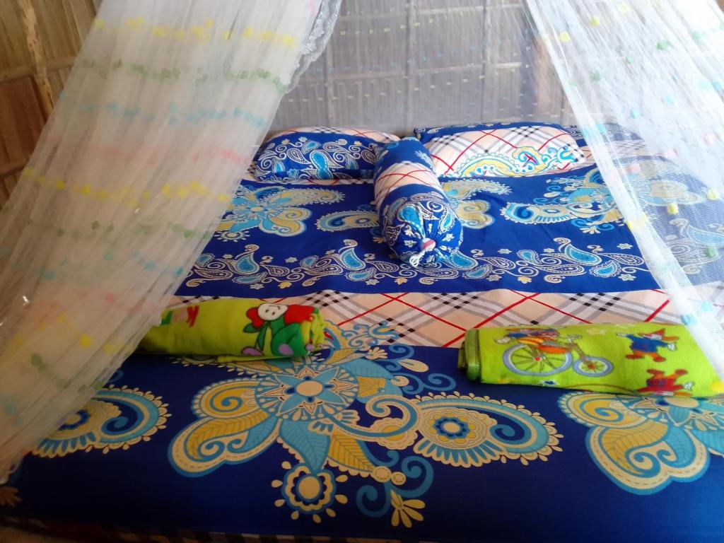 a bed with a blue comforter and pillows at Snonbepur homestay Raja Ampat in Sageurin