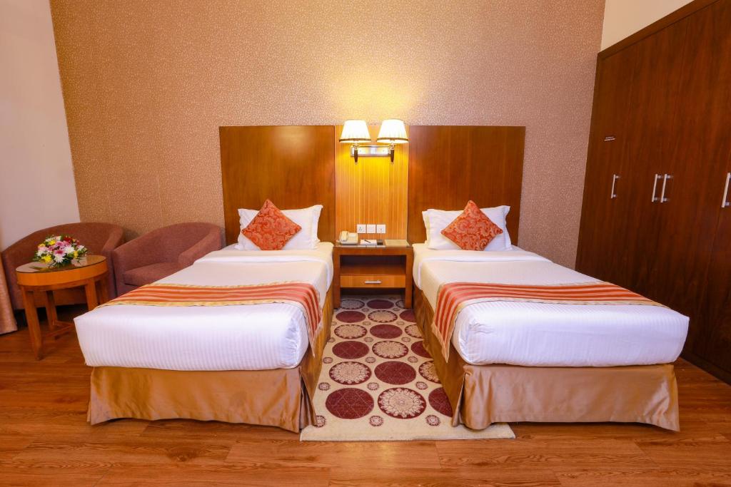 a hotel room with two beds and a table at Fortune Pearl Hotel in Dubai