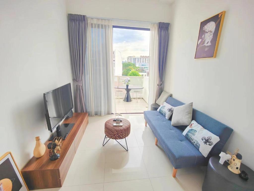 een woonkamer met een blauwe bank en een tv bij Centralize Stylish Loft Apartment Beside Mrt 摩登小屋 in Singapore