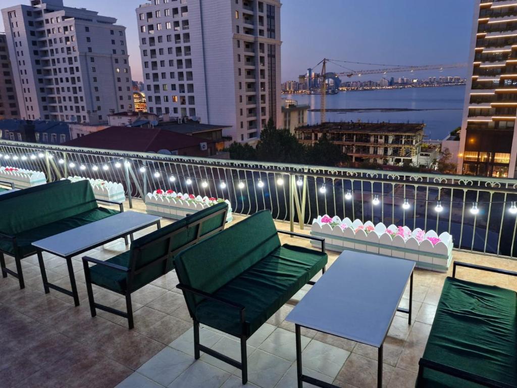 a rooftop patio with tables and chairs and lights at Nur Hotel Sea View in Baku