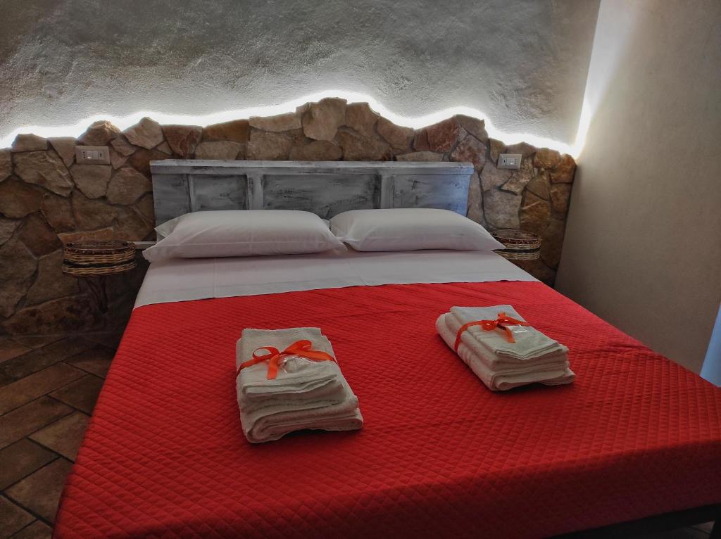 ein Schlafzimmer mit einem roten Bett mit Handtüchern darauf in der Unterkunft TIK TAK B&B diffuso in Verbicaro