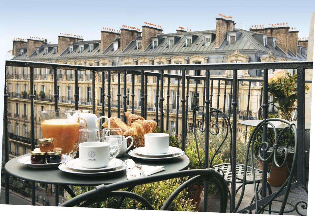 a table with cups of coffee and pastries on a balcony at Hôtel du Danube Saint Germain in Paris