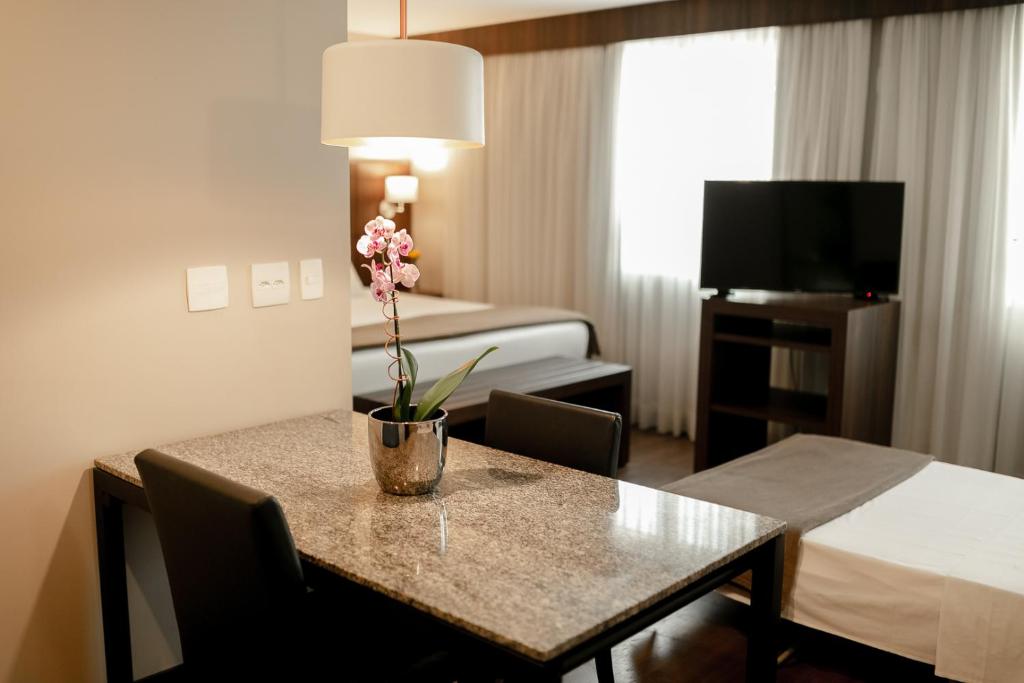 ein Hotelzimmer mit einem Tisch mit einer Blumenvase darauf in der Unterkunft Bourbon Ponta Grossa Convention Hotel in Ponta Grossa