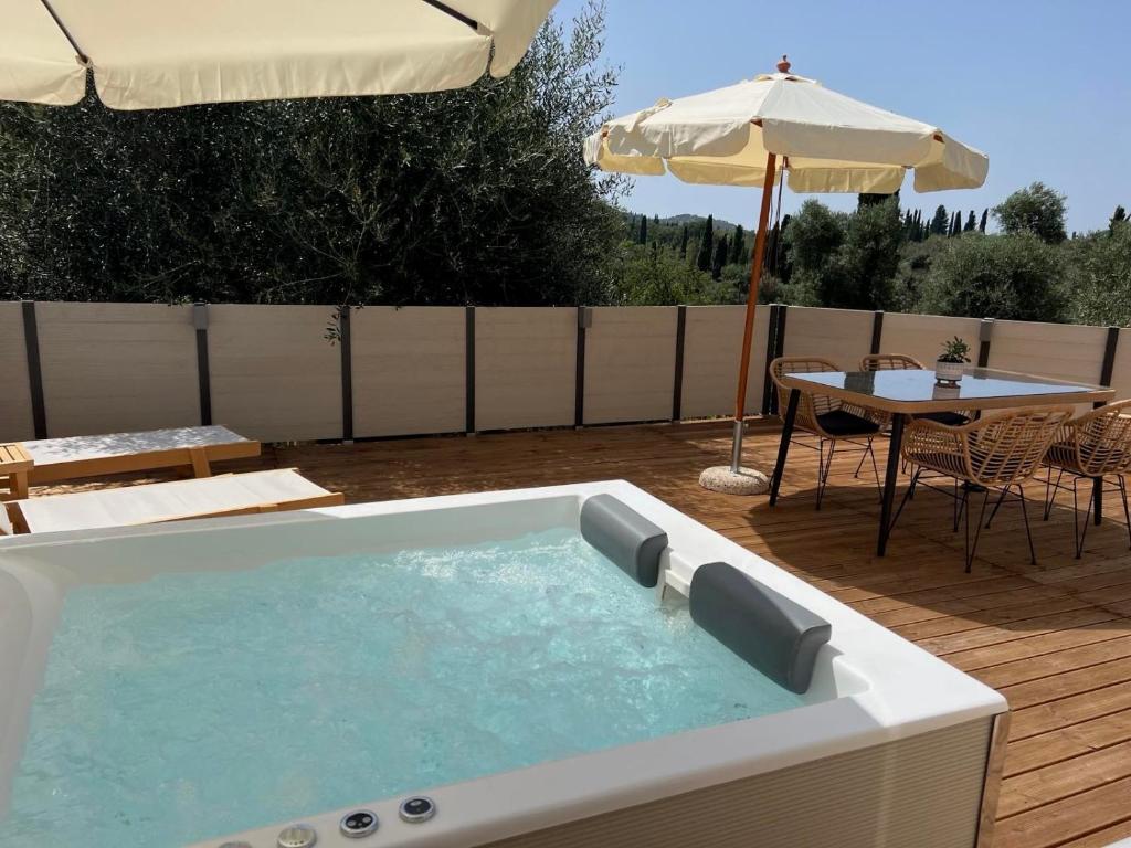 bañera de hidromasaje en una terraza con mesa y sombrilla en Minerva Estate Corfu, en Alepochórion