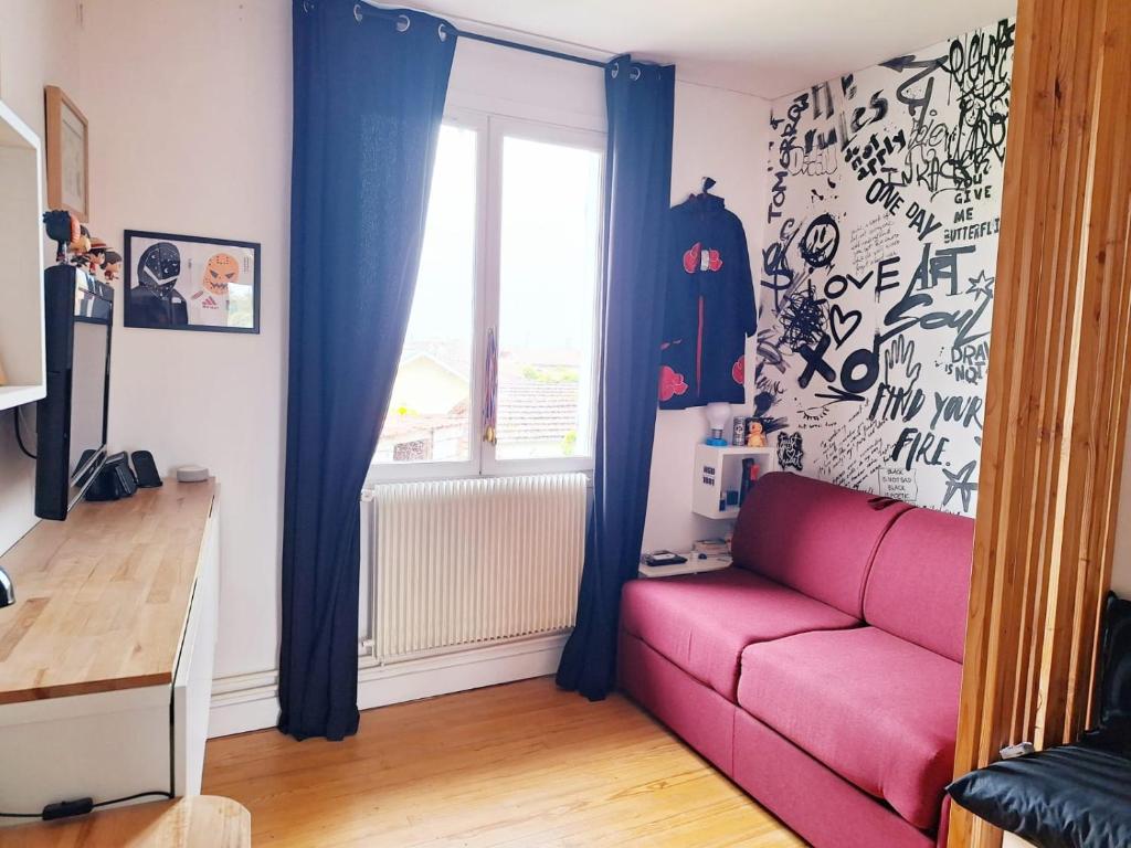 a living room with a pink couch and a window at Maison du bonheur in Lanton