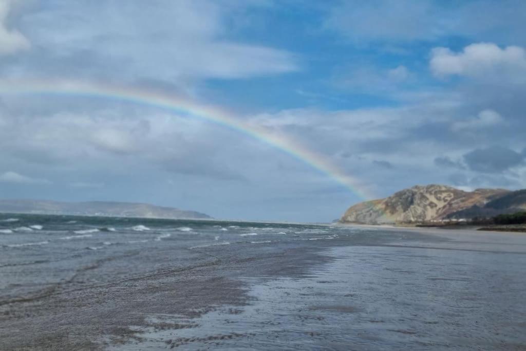 einen Regenbogen über einem Strand mit dem Meer in der Unterkunft 16 Cambrian Court - New apartment with stunning sea views in Penmaen-mawr
