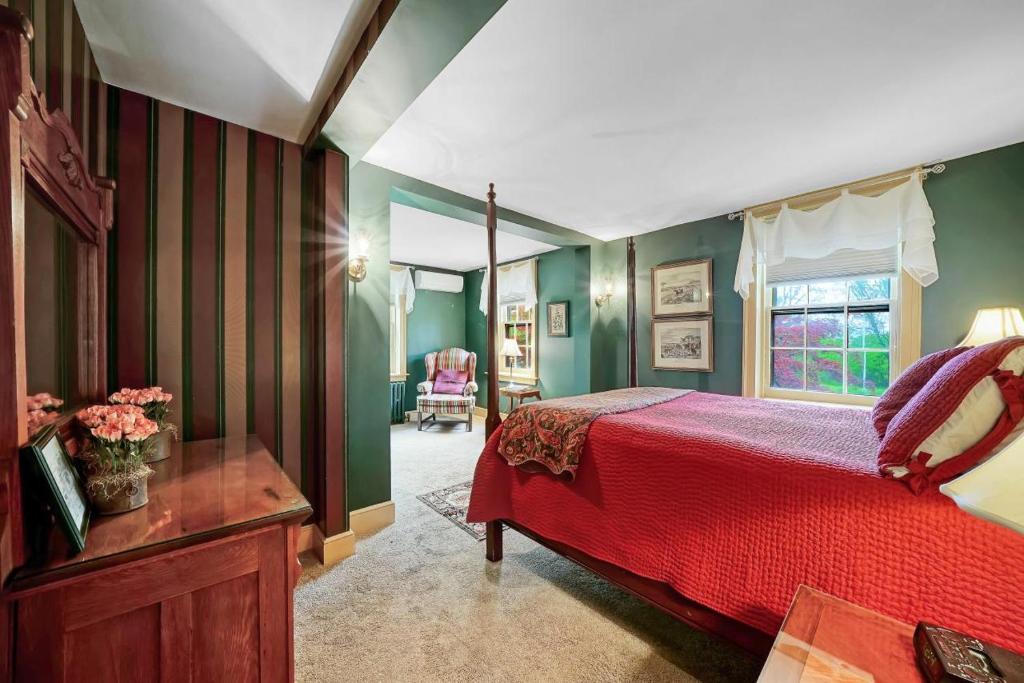 - une chambre avec un lit rouge et des murs verts dans l'établissement Cromwell Manor Inn, à Cornwall-on-Hudson