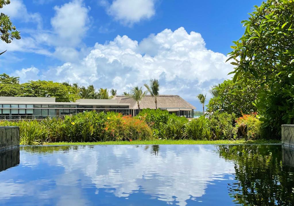 uma casa com um lago em frente a um edifício em Private Beach 5-star Villa, Golf & Luxe em Centre de Flacq