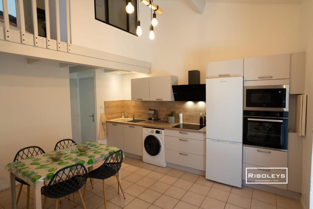 une cuisine avec une table et un réfrigérateur blanc dans l'établissement Villa rénovée climatisée à 500m de la plage, à Vias