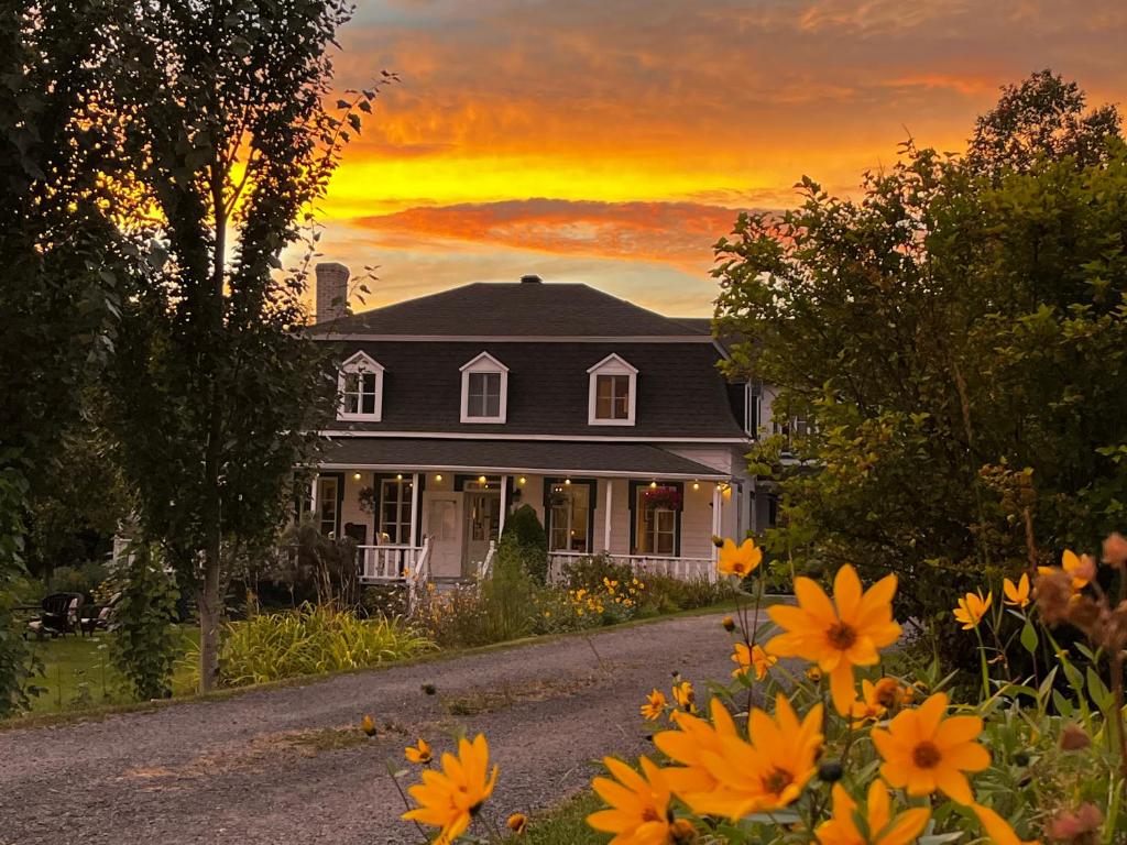 a house at sunset with flowers in the foreground at Auberge musicale Pour un Instant in La Malbaie