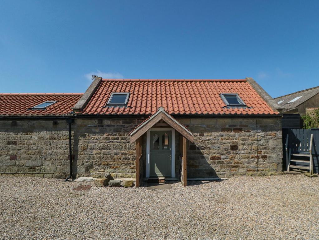 a stone house with a green door and a red roof at Barn Cottage in Whitby