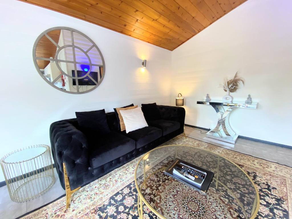 ein Wohnzimmer mit einem schwarzen Sofa und einem Glastisch in der Unterkunft Magpie 2 Hot Tub HuntersMoon-Warminster-Longleat-Wiltshire in Warminster