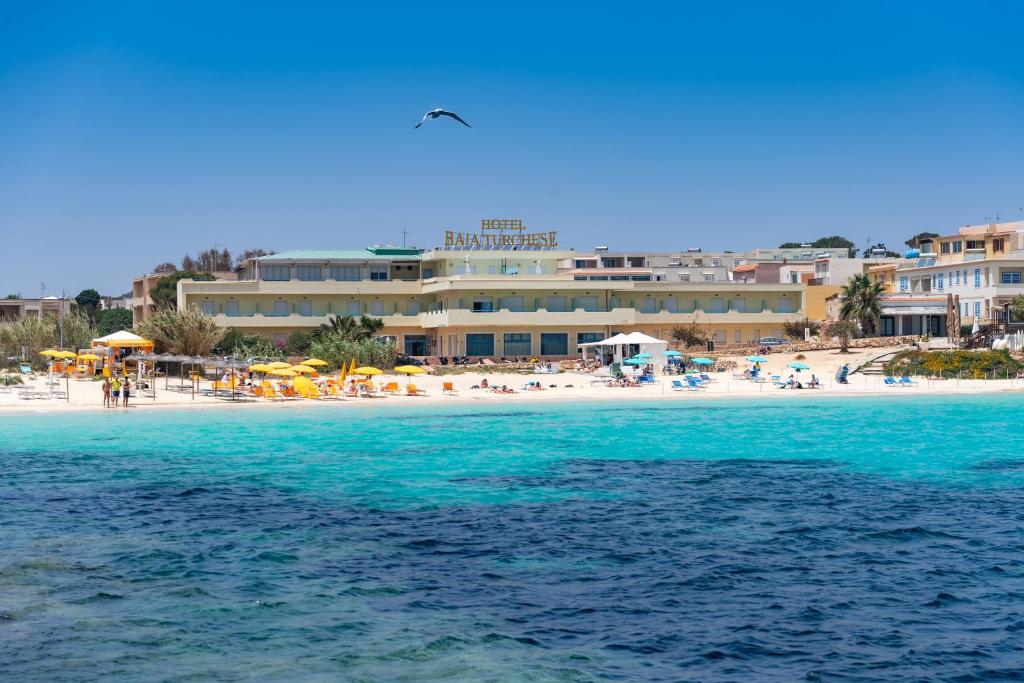 Blick auf den Strand mit Hotel und Meer in der Unterkunft Hotel Baia Turchese in Lampedusa