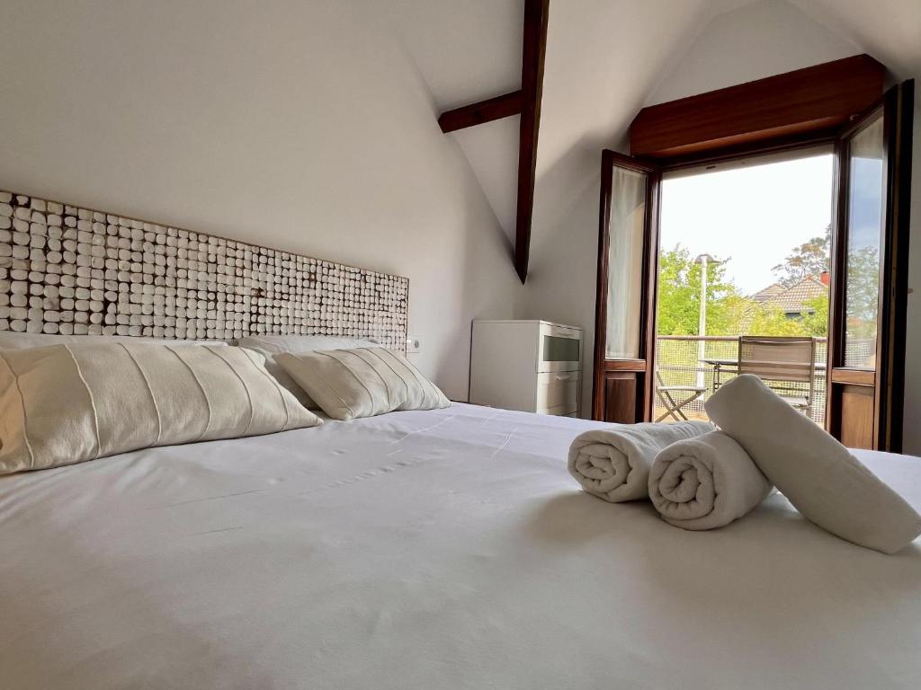 a bedroom with a large white bed with towels on it at Apartamento La Fuente - Monabri in Somo