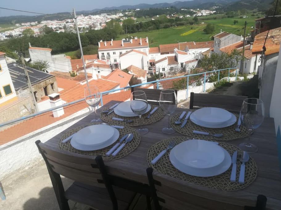 a table with white plates and glasses on a balcony at Casinhas Proença - Friends in Aljezur