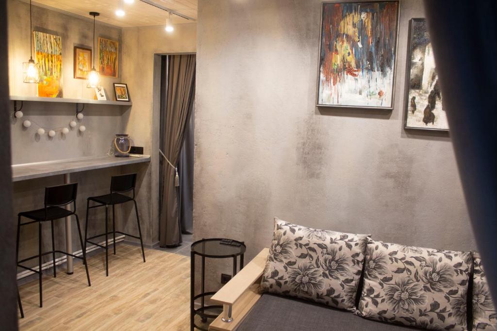a living room with a couch and a bar with stools at City center Artmania apartments in Chişinău