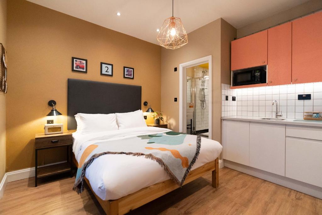 a bedroom with a large bed and a kitchen at room2 Hammersmith Townhouse in London