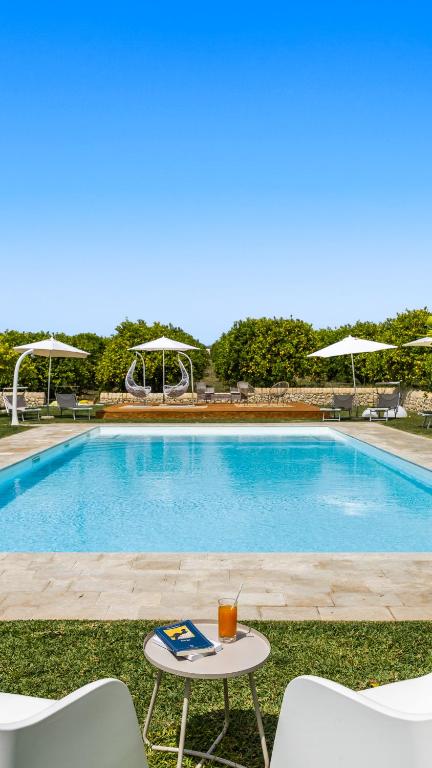 a swimming pool with a table and chairs next to it at Fiore di Vendicari B&B - Sicilian Charme, Lemon Grove and Sea in Noto