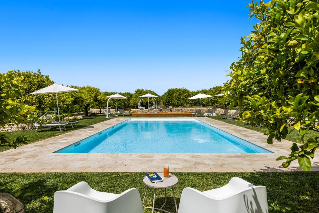 a pool with chairs and umbrellas in a yard at Fiore di Vendicari B&B - Sicilian Charme, Lemon Grove and Sea in Noto