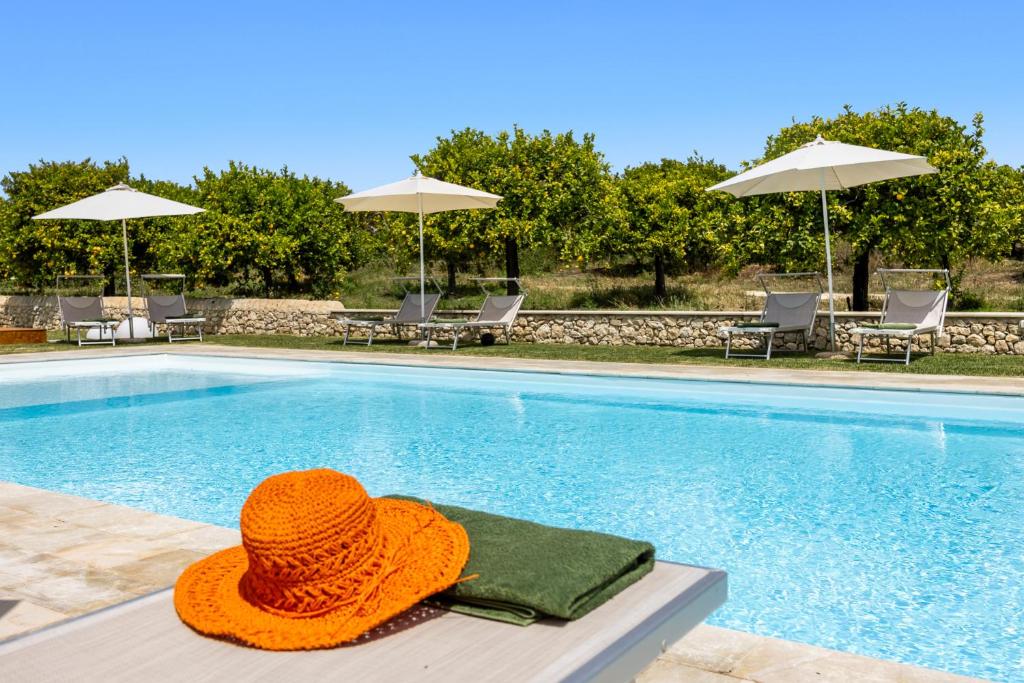 an orange hat sitting next to a swimming pool at Fiore di Vendicari B&B - Sicilian Charme, Lemon Grove and Sea in Noto