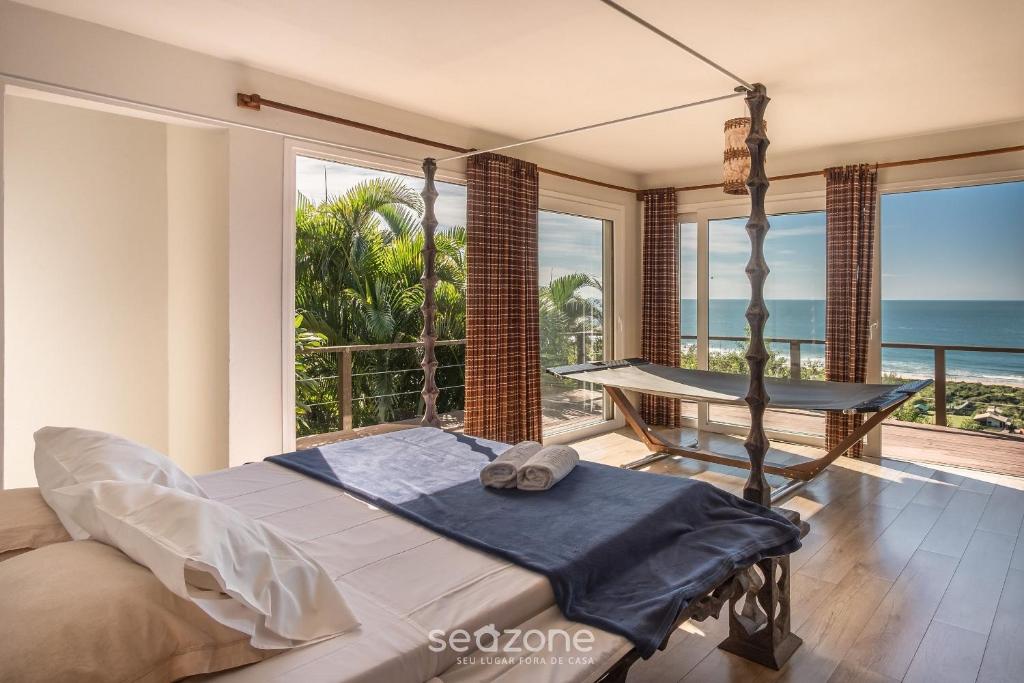 een slaapkamer met een bed en een balkon met uitzicht op de oceaan bij Casa com vista p mar em Garopaba PSV000 in Garopaba