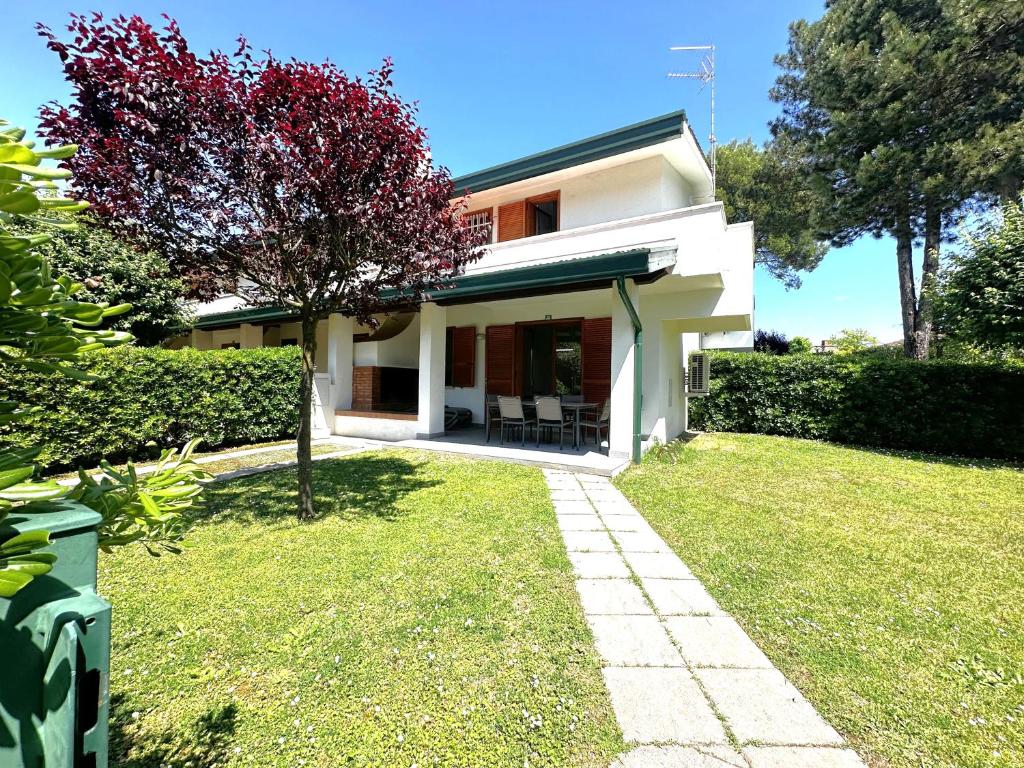 a white house with a green yard with a tree at Villaggio Danubio in Bibione