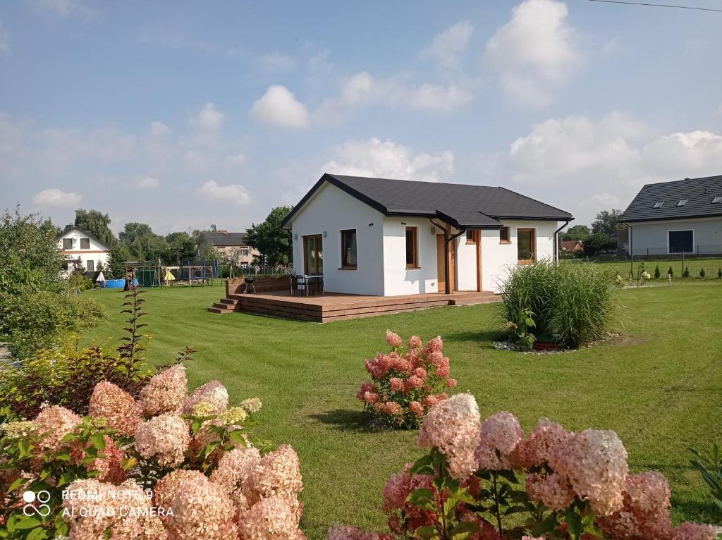 a small white house in a yard with flowers at Domek agroturystyczny in Zawada