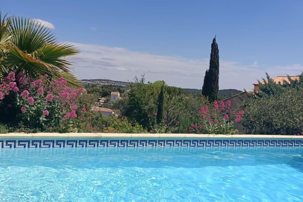 - une piscine dans une cour ornée de fleurs et d'arbres dans l'établissement Bel appartement dans villa avec piscine, à Combaillaux
