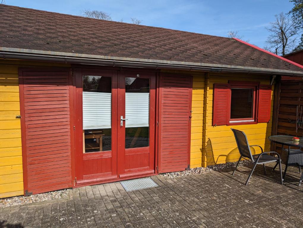 Casa amarilla y roja con mesa y sillas en Ferienhaus 2, en Ludorf