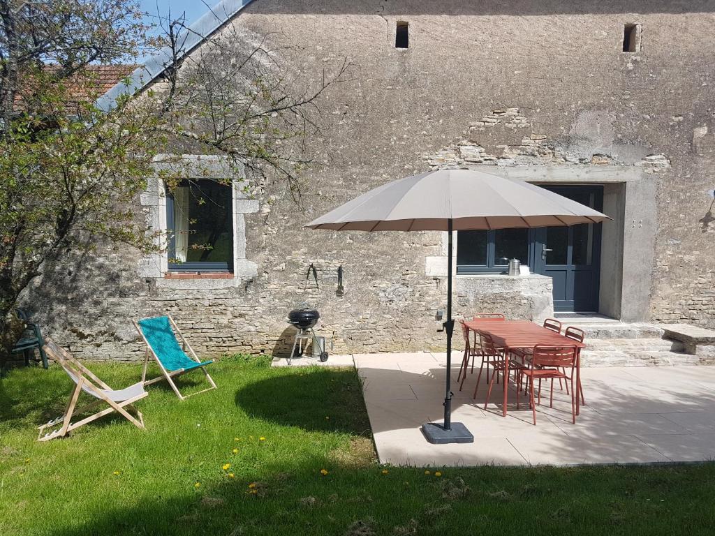 a table and chairs and an umbrella in a yard at Le Cottage in Sorans-lès-Breurey