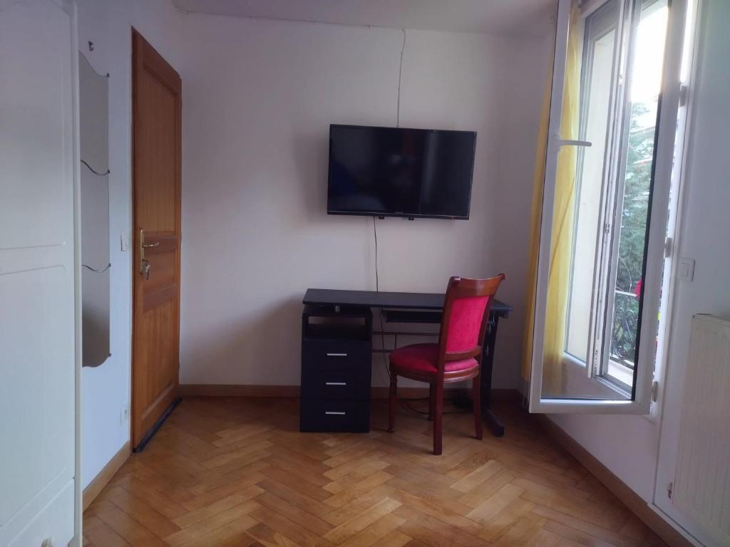 Cette chambre comprend un bureau avec une télévision et une chaise. dans l'établissement Chambre de charme sur jardin, à Courbevoie