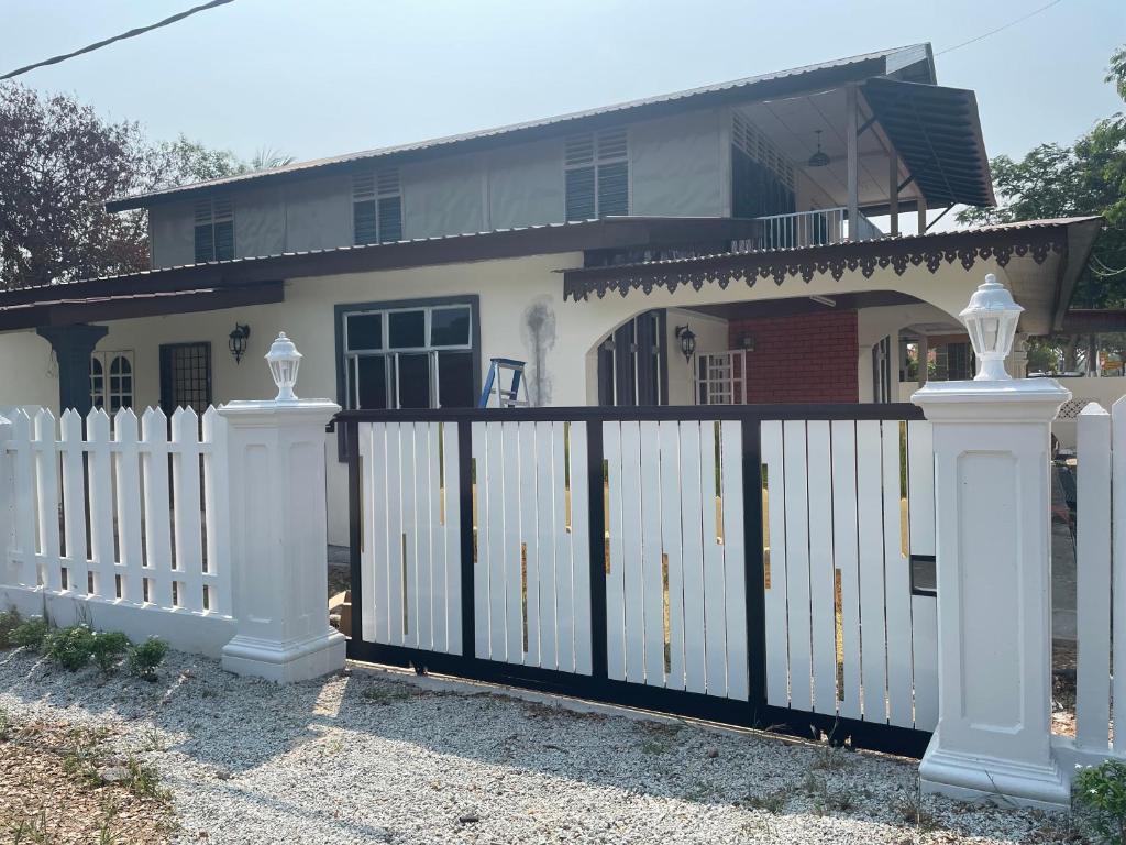 a white fence in front of a house at Rossini Home in Muar