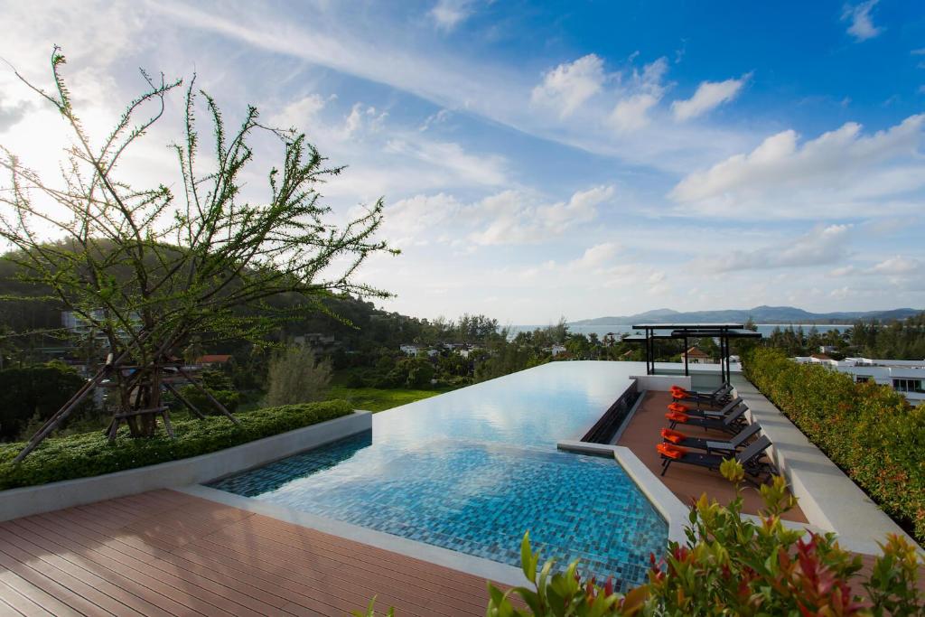 a swimming pool with lounge chairs and a view of the city at Comfy 1 Bedroom Condo in Surin (Seaview Rooftop Pool & Gym) in Phuket Town
