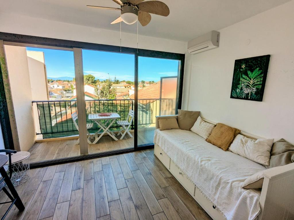 d'un salon avec un canapé et un balcon. dans l'établissement Studio climatisé avec balcon - Vue montagne - 50 m de la plage, à Canet
