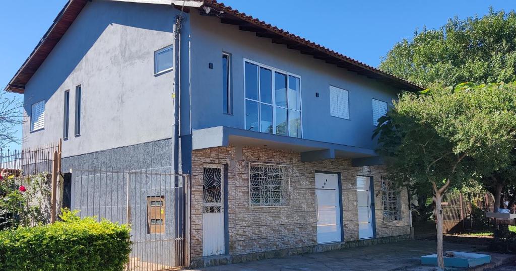 una casa azul y blanca con una valla en Apartamento modelo chalé 201, en Santo Ângelo