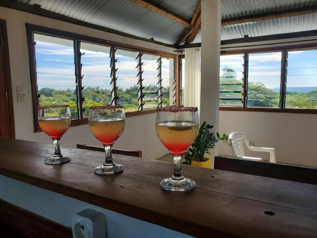 three wine glasses sitting on top of a wooden table at Rooftop avec vue panoramique, à 200m de la plage in Mahajanga