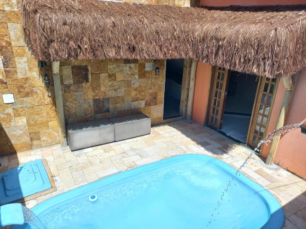 a swimming pool in front of a building with a thatch roof at Casa Recanto do sol in Natal