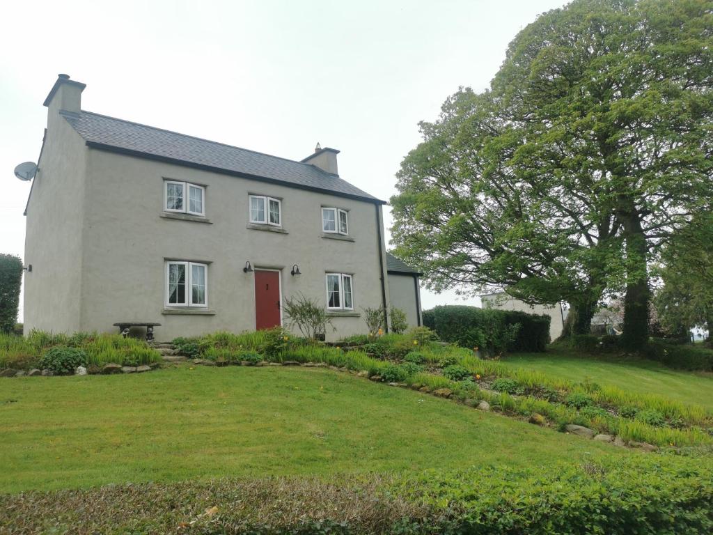 a white house with a red door and a yard at Christie's Cottage in Dungiven