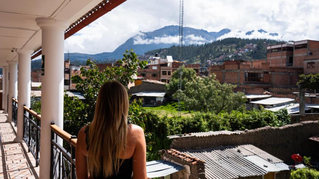 a woman sitting on a balcony looking at the mountains at Tupac Huaraz in Huaraz