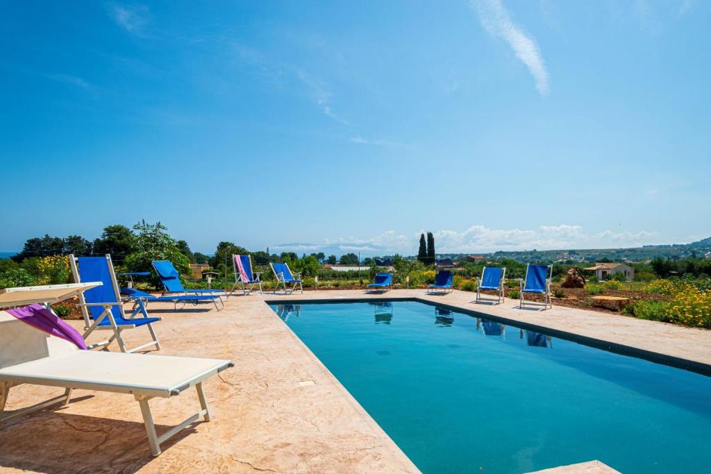 un groupe de chaises assises autour d'une piscine dans l'établissement Villa Maguetta with private pool in Scopello, à Scopello