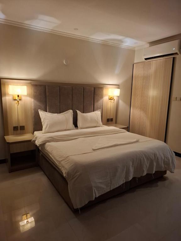 1 dormitorio con 1 cama grande y 2 luces encendidas en بلند للشقق المخدومة, en Dammam