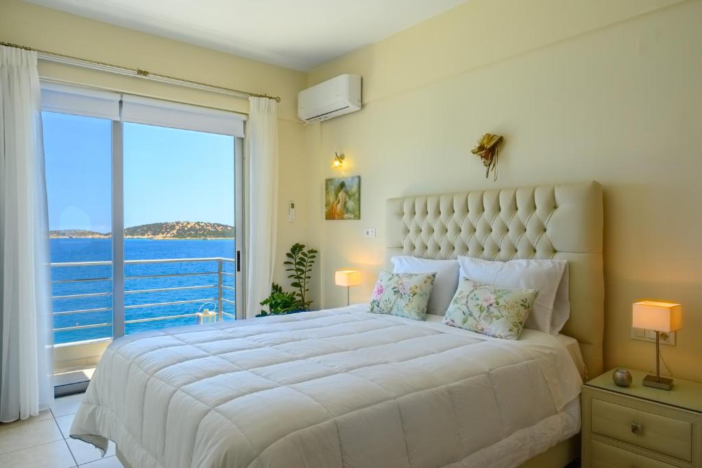 a bedroom with a large bed with a view of the ocean at Perla Apartments in Agios Nikolaos